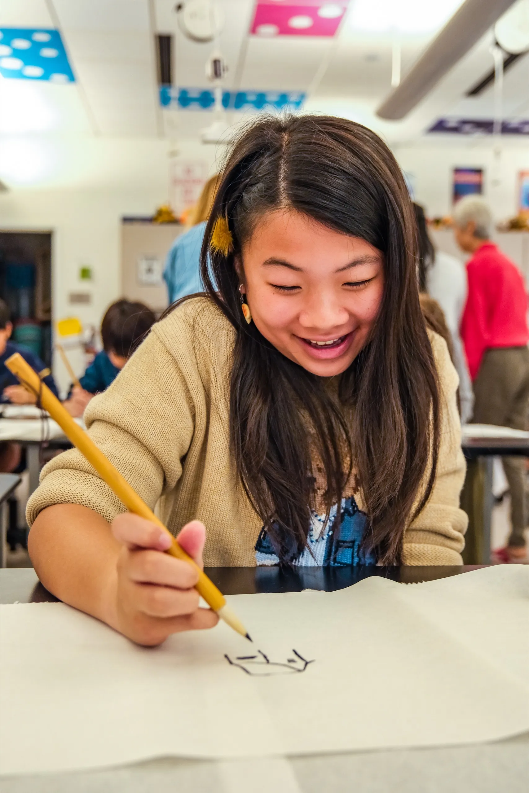 A Middle School student smiles as she sketches with a pencil in art class