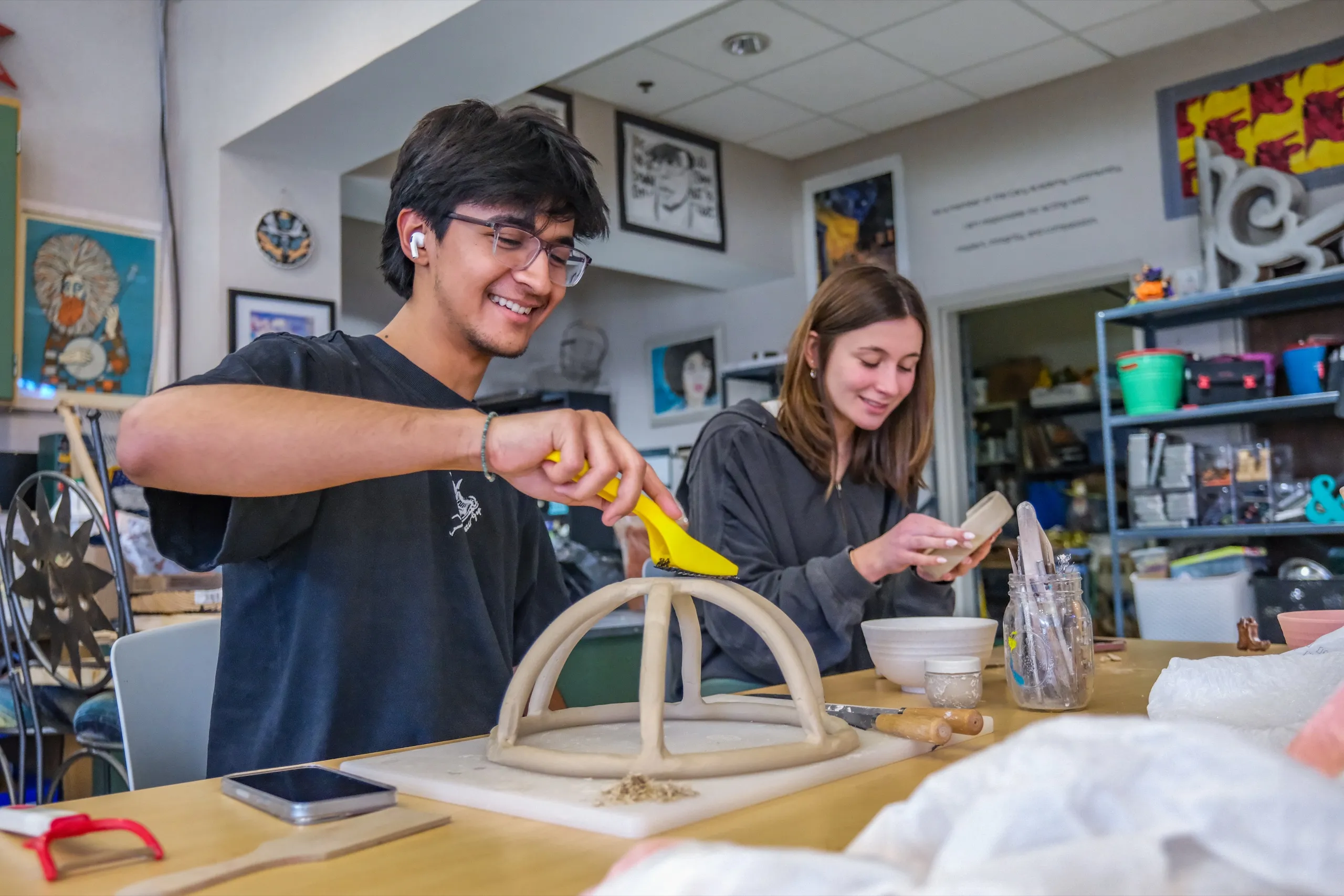 An Upper School student glues the last strut onto a balsa-wood arch while a classmate works beside him